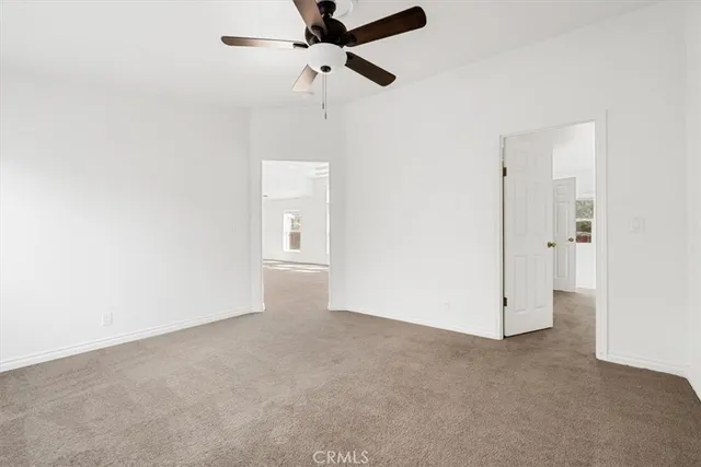 an empty room with closet and a ceiling fan