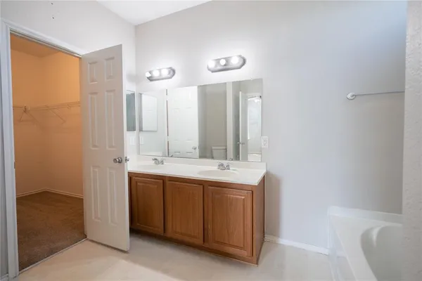 a bathroom with a double vanity sink and mirror with bathtub