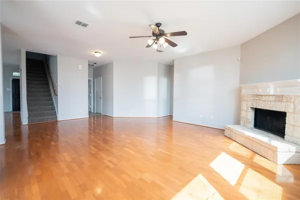 a view of an empty room with wooden floor and a fireplace