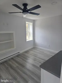 an empty room with wooden floor fan and windows