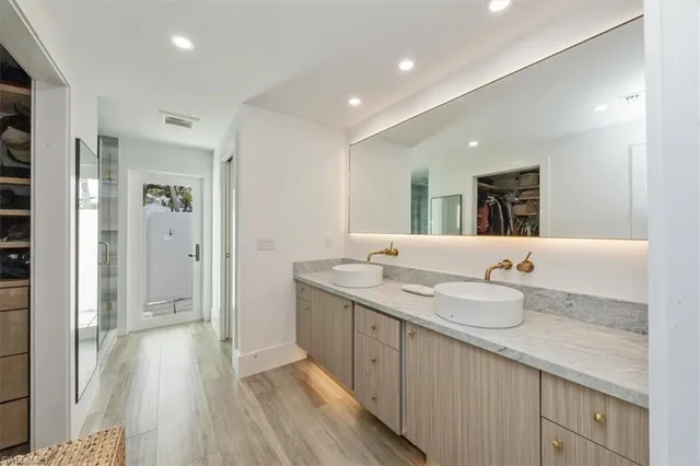 a bathroom with a granite countertop double vanity sink and mirror