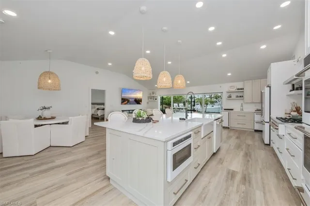 a large kitchen with kitchen island a stove a sink a refrigerator and glass cabinets with wooden floor