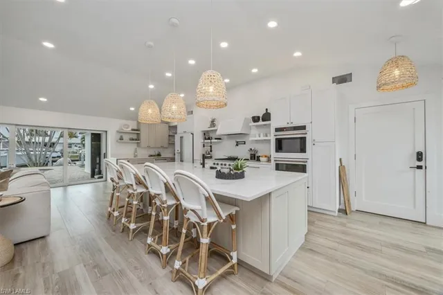 a kitchen with stainless steel appliances a dining table chairs and wooden floor