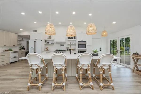 a kitchen with stainless steel appliances kitchen island granite countertop a dining table chairs and view living room