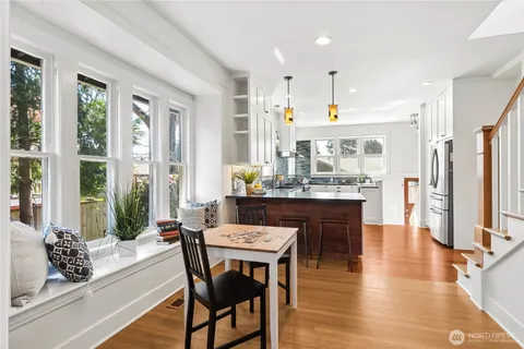 a dining hall with stainless steel appliances kitchen island granite countertop a table chairs and a refrigerator