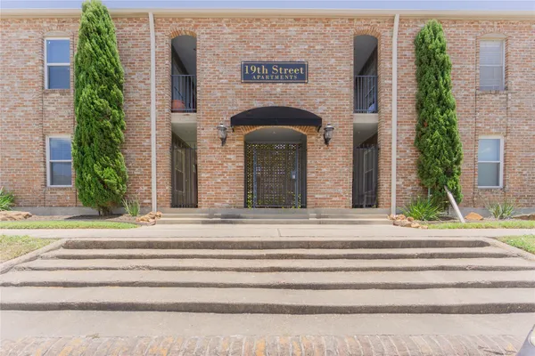 a front view of a building with a garden and plants
