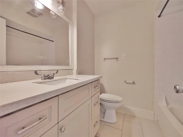 a bathroom with a granite countertop sink a toilet and a mirror