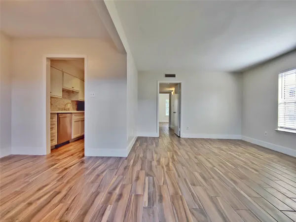 a view of empty room with wooden floor and window
