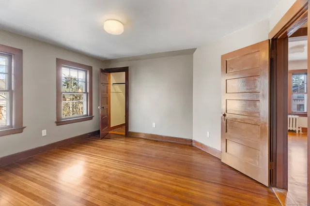 an empty room with wooden floor closet and windows
