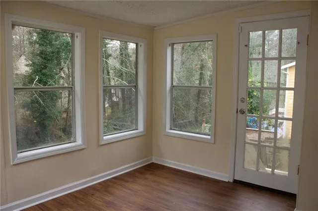 a view of an empty room with wooden floor and windows
