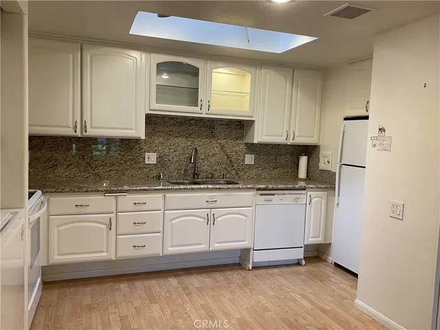 a kitchen with stainless steel appliances granite countertop a stove a sink and white cabinets