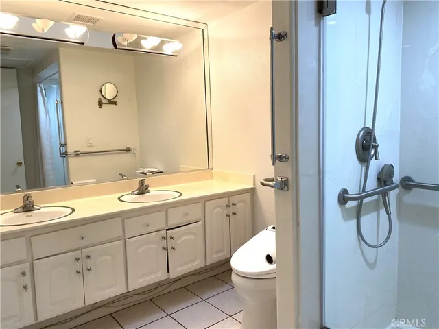 a bathroom with a double vanity sink toilet mirror and shower