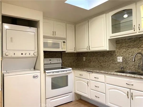 a kitchen with granite countertop white cabinets and white appliances