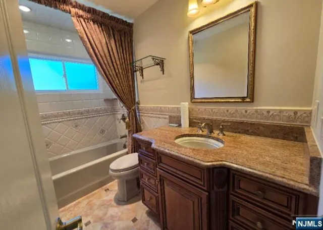 a bathroom with a granite countertop toilet sink and mirror