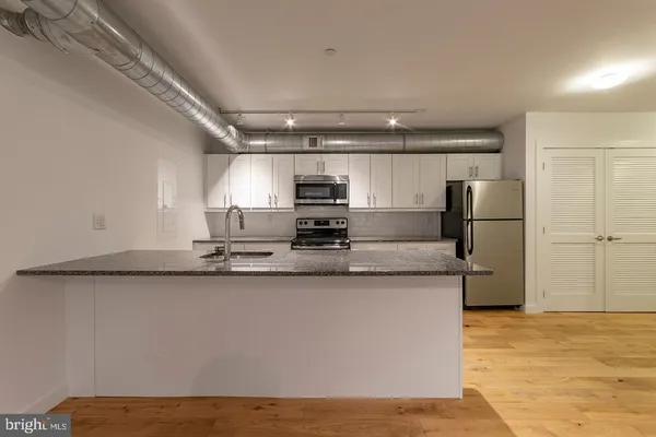 a kitchen with stainless steel appliances granite countertop a sink refrigerator and microwave
