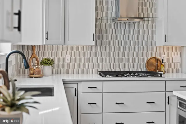 a room with stainless steel appliances kitchen island granite countertop a stove a sink a dining table and chairs with wooden floor