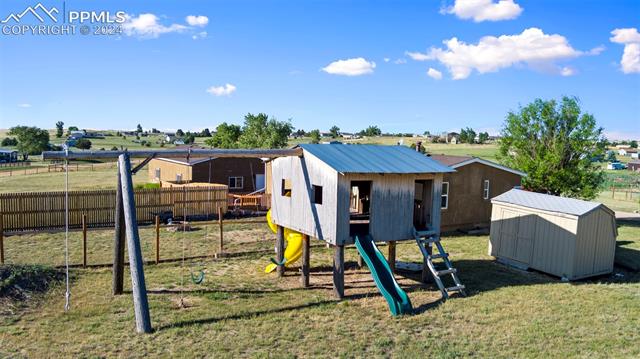 View of play area with a yard and a shed