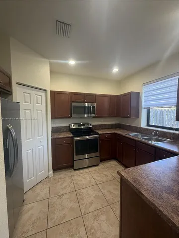 a large kitchen with stainless steel appliances granite countertop a stove and a refrigerator