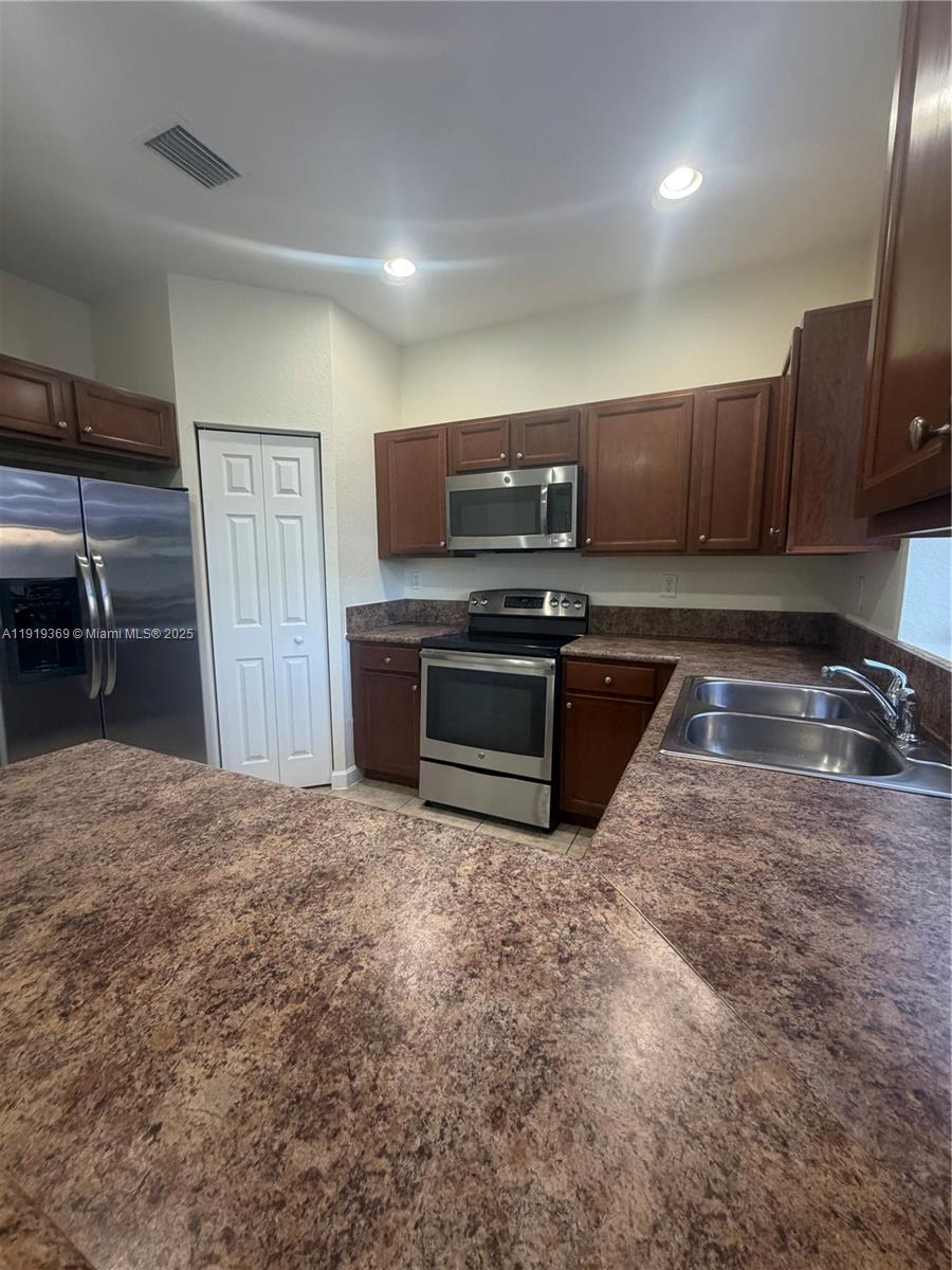 11347 Southwest 232nd Terrace Homestead, FL 33032 - Photo 7 of 26 a kitchen with granite countertop a sink and stainless steel appliances