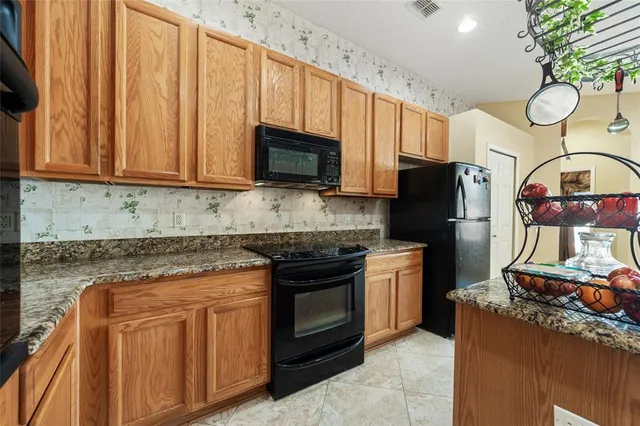 a kitchen with stainless steel appliances granite countertop a stove top oven a refrigerator and a microwave