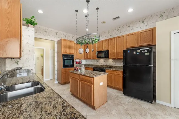a kitchen with stainless steel appliances granite countertop a refrigerator a sink dishwasher a stove and white cabinets
