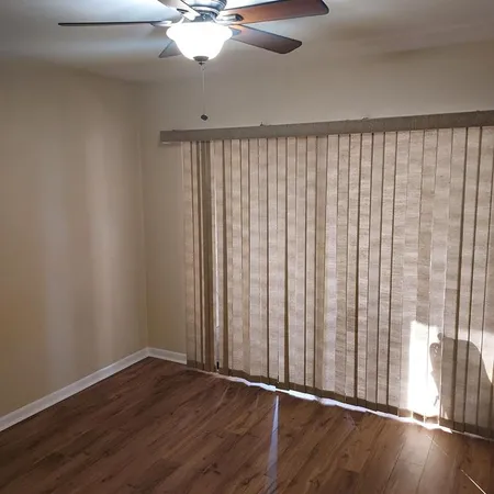 a view of an empty room with wooden floor and a window