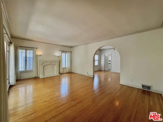 a view of empty room with wooden floor and window