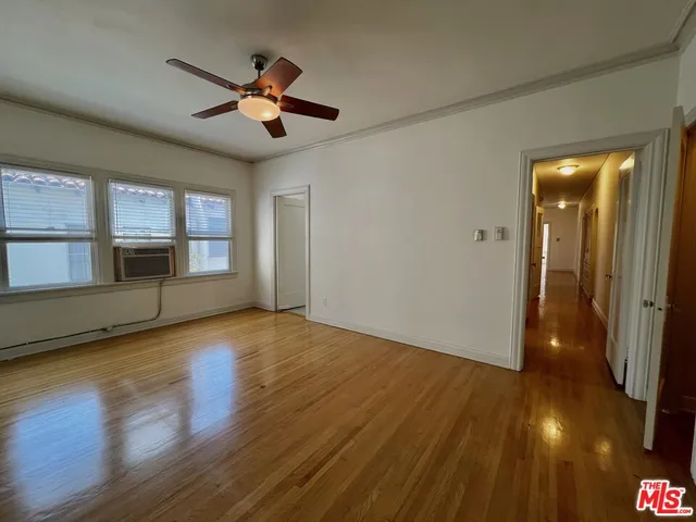 a view of empty room with wooden floor and fan