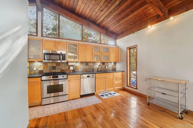 a kitchen with stainless steel appliances granite countertop a refrigerator a stove and a sink with wooden floor