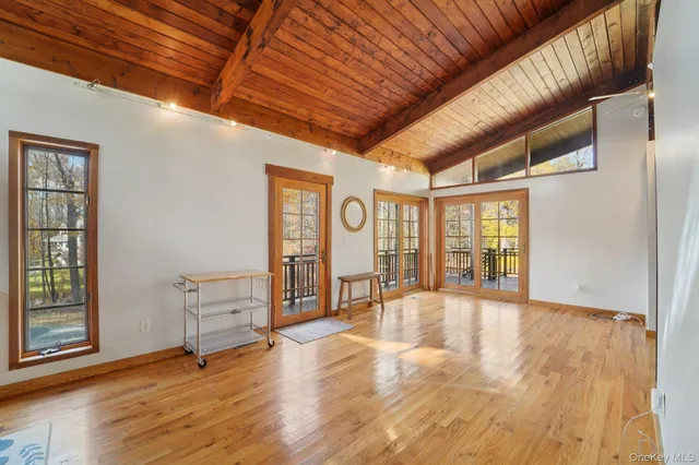 a view of an empty room with window and wooden floor