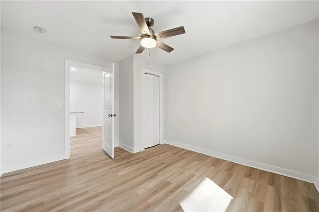 an empty room with wooden floor and a ceiling fan