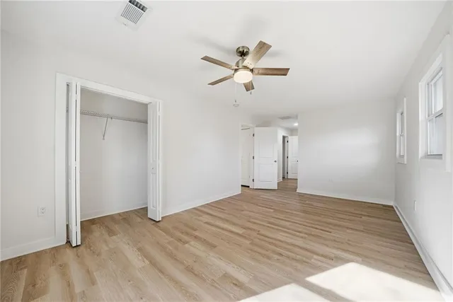 a view of empty room with wooden floor and ceiling fan