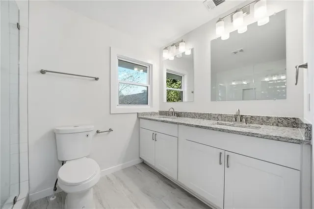 a bathroom with a granite countertop toilet a sink and a mirror