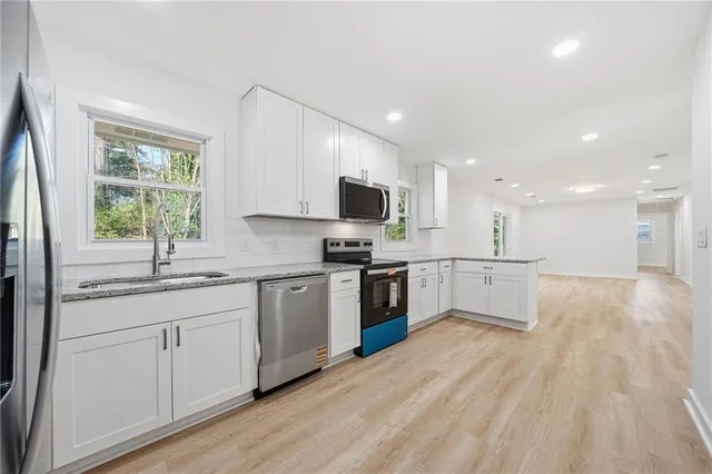 a kitchen with stainless steel appliances granite countertop a stove top oven a sink dishwasher and a refrigerator with wooden floor