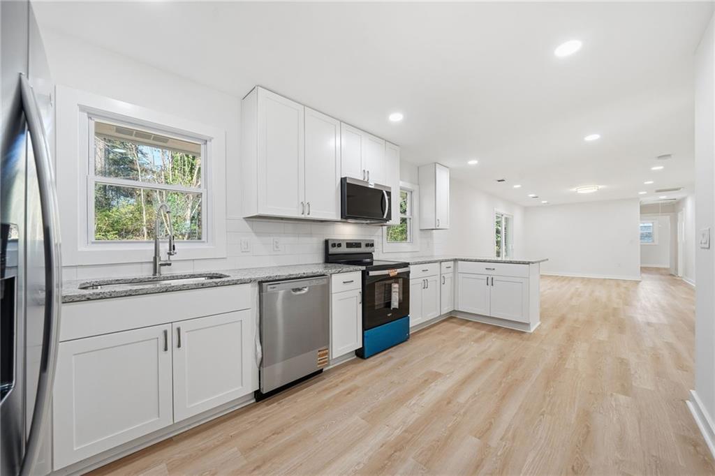 1136 Powell Court Southeast Atlanta, GA 30316 - Photo 7 of 33 a kitchen with stainless steel appliances granite countertop a stove top oven a sink dishwasher and a refrigerator with wooden floor