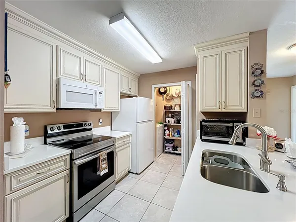 a living room with stainless steel appliances furniture a rug and a kitchen view