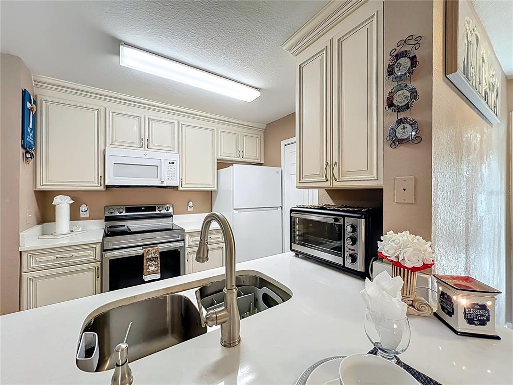 5471 Vineland Road, Unit 7109 Orlando, FL 32811 - Photo 19 of 60 a kitchen with stainless steel appliances granite countertop a sink a stove and a refrigerator