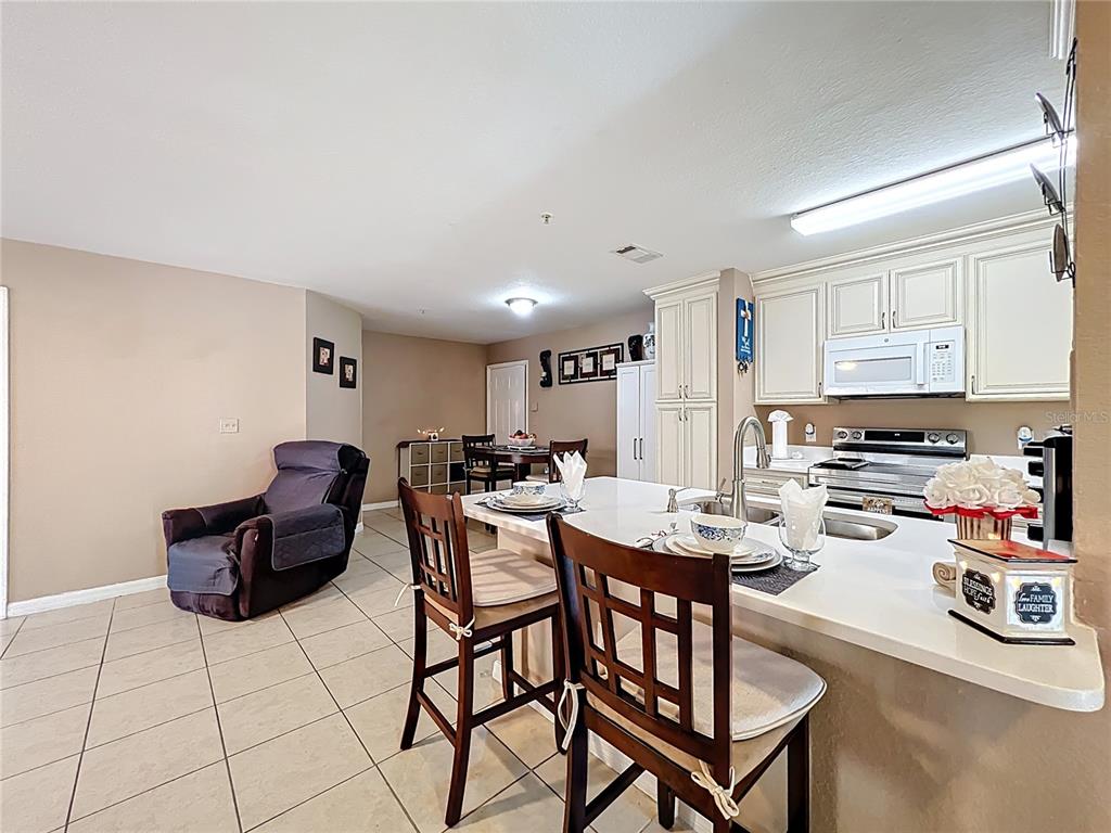 5471 Vineland Road, Unit 7109 Orlando, FL 32811 - Photo 21 of 60 a living room with stainless steel appliances furniture a rug and a kitchen view