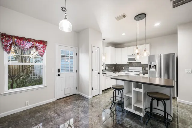a kitchen with a refrigerator a stove a sink and white cabinets