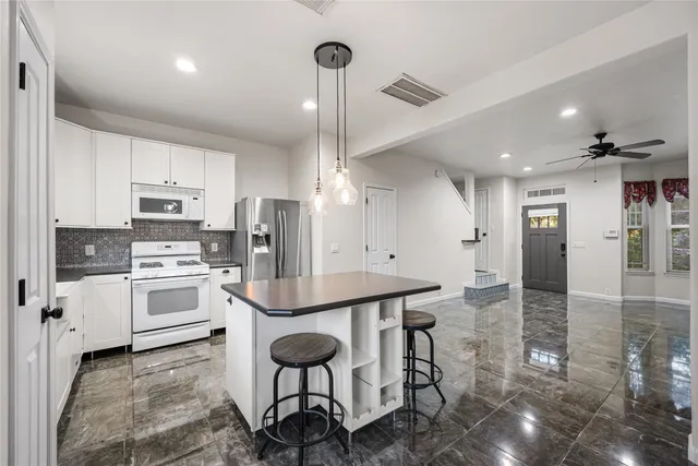 a kitchen with stainless steel appliances kitchen island granite countertop a stove a sink and a refrigerator with wooden floor