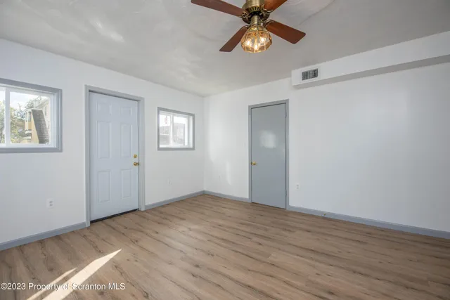 a view of an empty room with a window and wooden floor