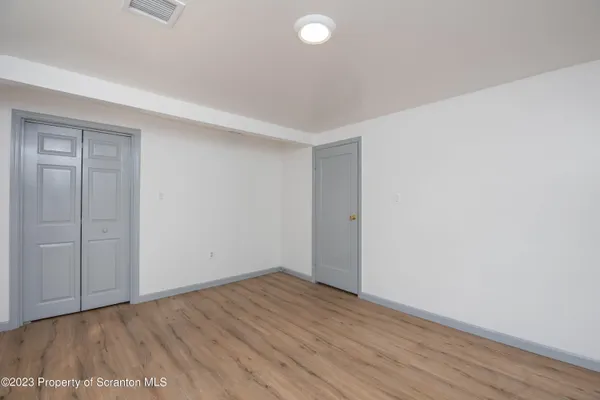 a view of an empty room with wooden floor and closet