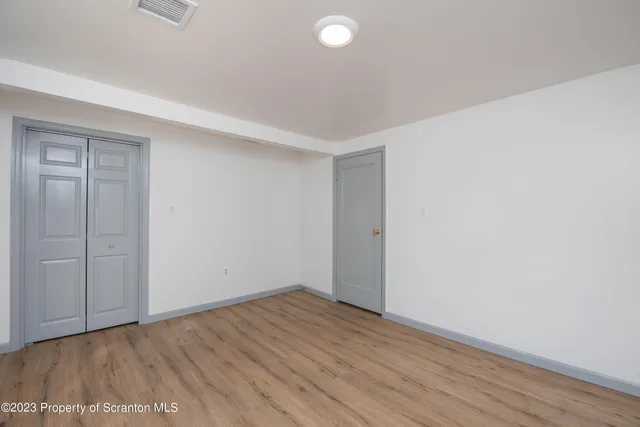 a view of an empty room with wooden floor and closet