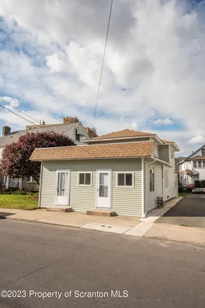 a view of a white house next to a yard with big trees