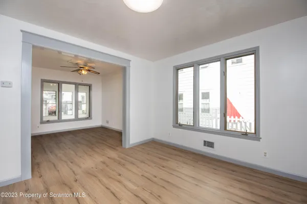 a view of an empty room with wooden floor and a window