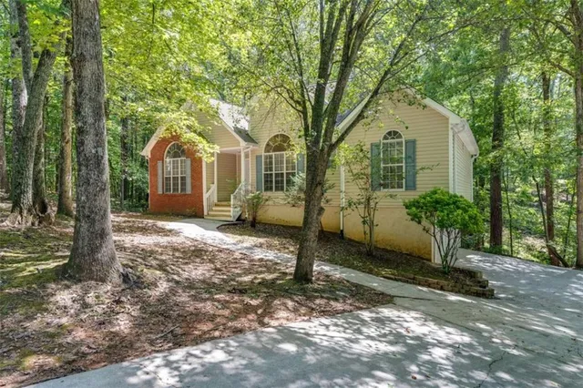 a front view of a house with a yard and large trees