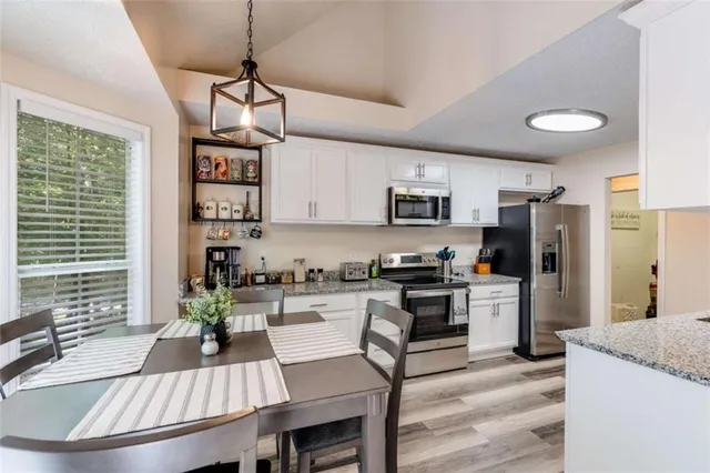 a kitchen with stainless steel appliances granite countertop a stove a refrigerator a sink a stove and white cabinets