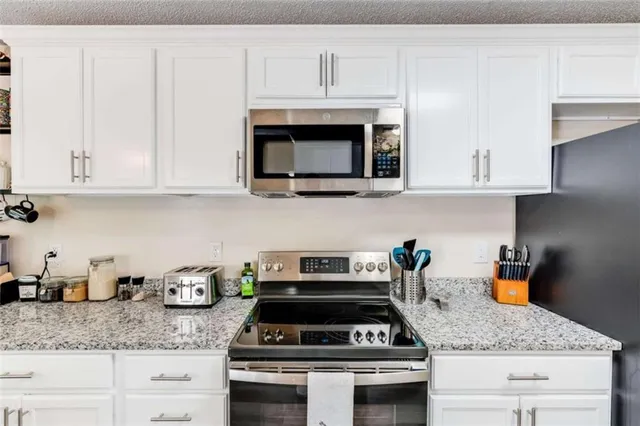 a kitchen with granite countertop a stove a microwave and cabinets