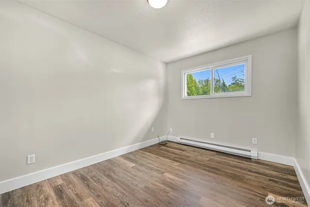 an empty room with wooden floor and window