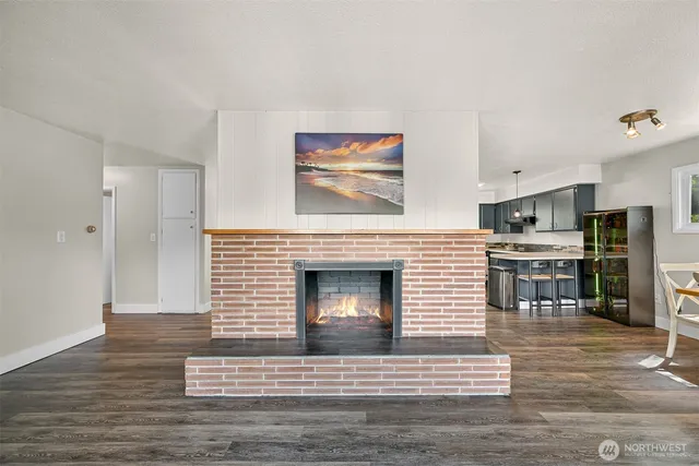 a living room with stainless steel appliances furniture a fireplace and wooden floor